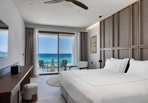 Modernes Hotelzimmer mit Doppelbett und großem Balkon mit Blick auf das blaue Meer.