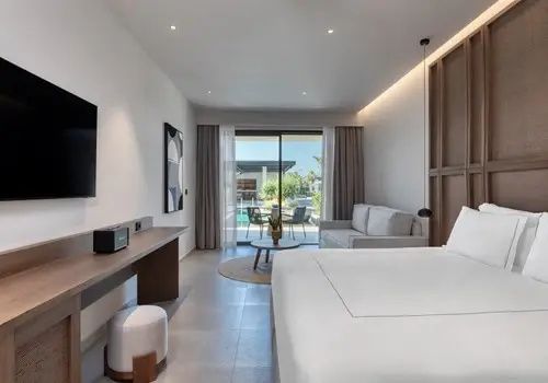 Modernes Hotelzimmer mit Doppelbett, Sofa und Blick auf die Terrasse durch Glasflügeltüren.