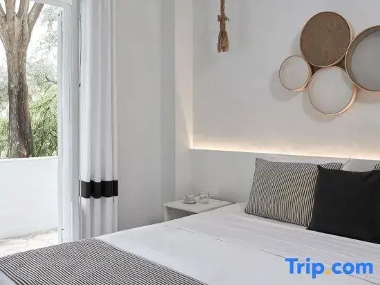 Modernes Hotelzimmer mit weißem Doppelbett, dekorativen Kissen und kreisförmigem Wandschmuck.