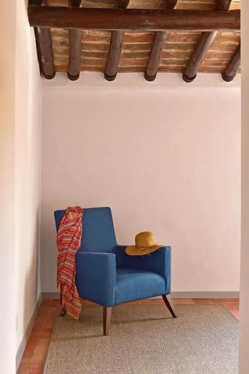 Blauer Sessel mit einem Strohhut und Tuch in einer ruhigen Zimmer-Ecke des Hotels.