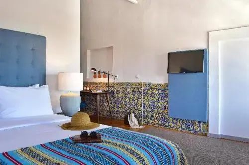 Schlafbereich im Hotelzimmer mit dekoriertem Bett, Schreibtisch und Fliesenborde an der Wand.