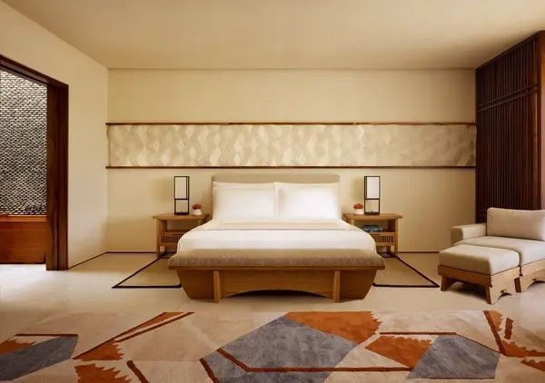 Doppelbett mit Holzrahmen, Nachttischen und dekorativer Wandverkleidung im Hotelzimmer.
