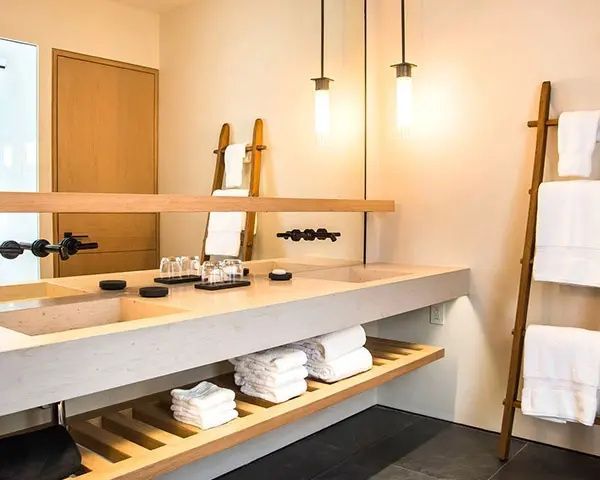 Badezimmer mit doppeltem Waschtisch, großer Spiegelfläche und Handtuchleiter aus Holz.