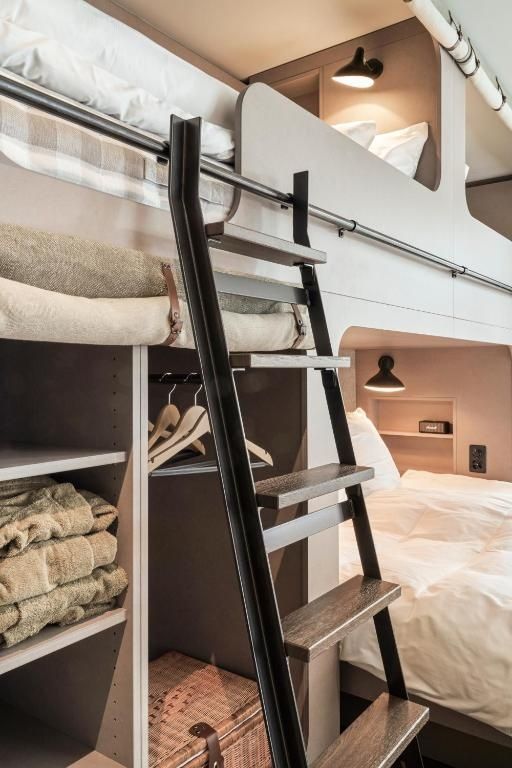 Schwarze Metallleiter an einem Etagenbett aus Holz mit Fach für Handtücher.