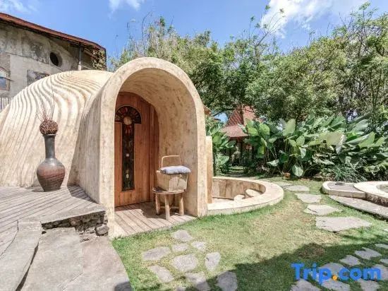 Gewölbter Eingang eines Gebäudes in organischer Architektur mit Gartenanlage.