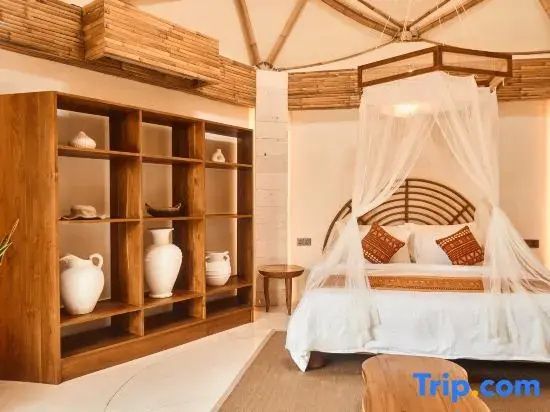 Holzregal mit weißen Vasen und ein Doppelbett unter einer gewölbten Bambusdecke.