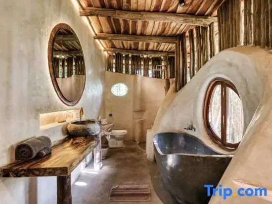 Badezimmer mit hölzernem Waschtisch, rundem Spiegel und dunkler Badewanne.