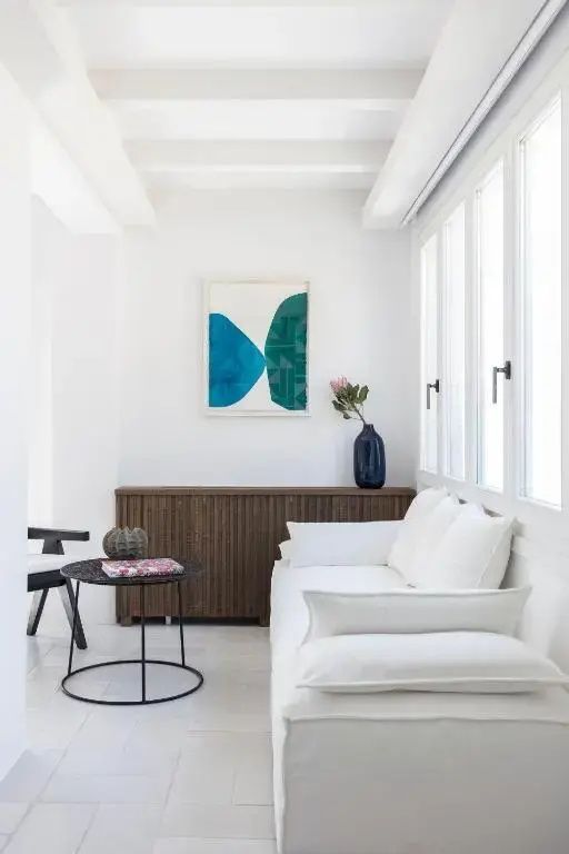 Sitzbereich mit weißem Sofa, schwarzem Beistelltisch und Kunstwerk an der Wand.
