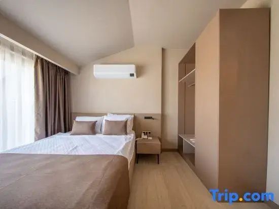 Doppelbett mit Kissen, Nachttisch und Klimaanlage in einem hellen Hotelzimmer.