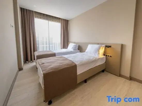 Hotelzimmer mit zwei Einzelbetten, hellen Wänden, Parkettboden und bodentiefem Fenster.
