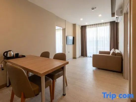 Wohnbereich einer Suite mit Holztisch, Stühlen, Sofa und Blick in das Schlafzimmer.