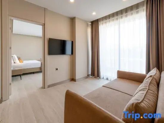 Sitzbereich der Suite mit braunem Sofa, Flachbildfernseher und Durchgang zum Schlafzimmer.