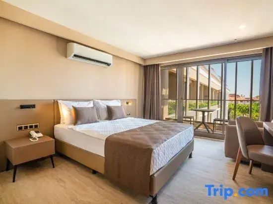 Doppelbett in hellem Hotelzimmer mit Klimaanlage und großem Fenster zum Balkon.