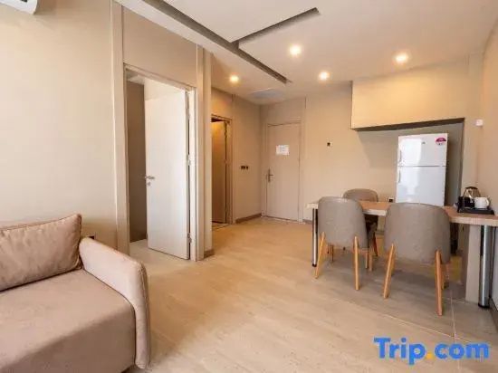 Wohnbereich einer Suite mit Sofa, Esstisch, Stühlen und einem Kühlschrank.