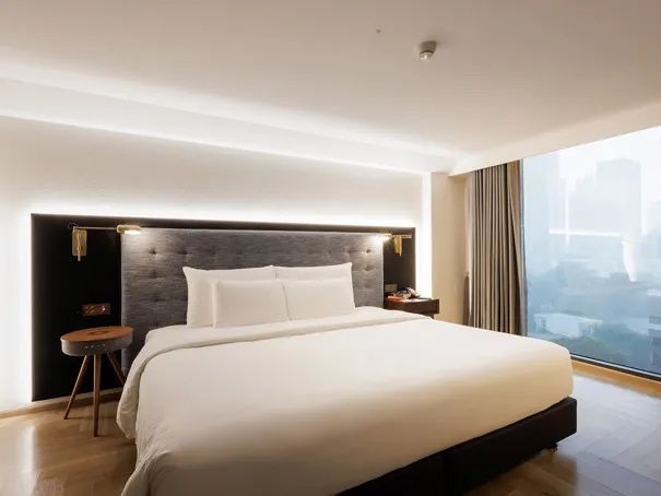 Hell eingerichtetes Schlafzimmer mit großem Bett und indirekter Beleuchtung.