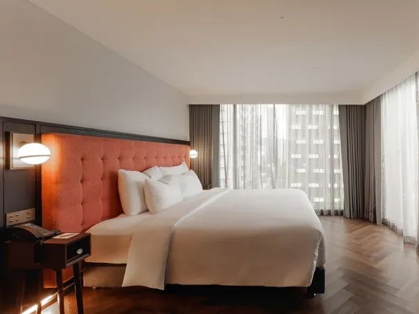 Modernes Schlafzimmer mit großem Bett, gepolstertem Kopfteil und hellem Holzfußboden.