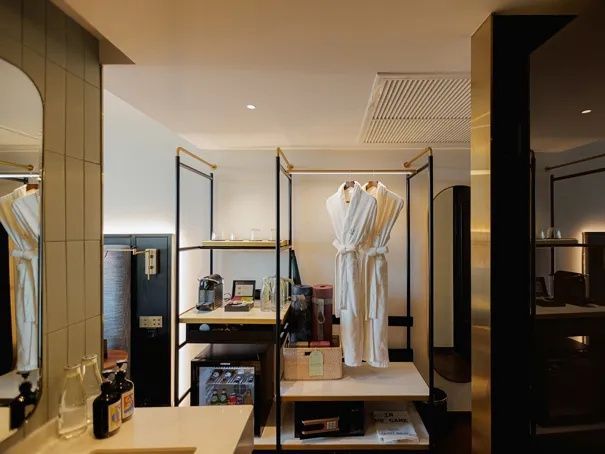 Offener Kleiderschrank mit zwei Bademänteln, Minibar, Kaffeemaschine und Safe im Hotelzimmer.