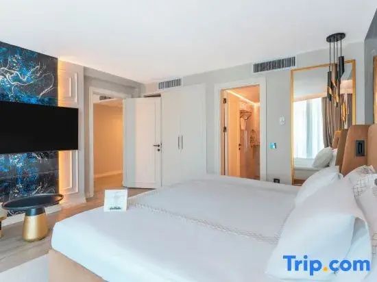 Hell eingerichtetes Hotelzimmer mit großem Doppelbett, Fernseher und Schrank.