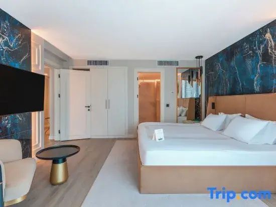 Modernes Hotelzimmer mit großem Bett, Beistelltisch und weißem Kleiderschrank.