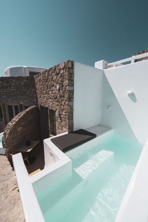 Privater Tauchbecken-Pool auf einer Terrasse mit Natursteinwand und weißer Fassade.