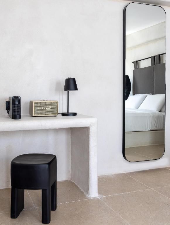 Weiß gemauerter Schreibtisch mit Lautsprecher, Lampe und Spiegel mit Blick auf das Bett.