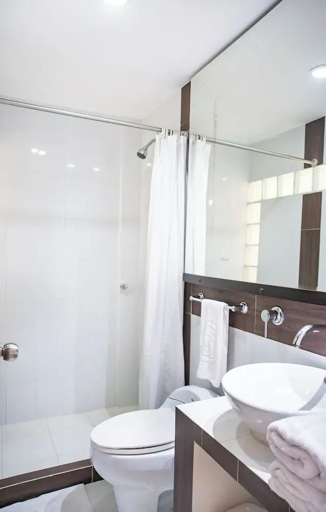 Badezimmer mit weißem Aufsatzwaschbecken, großem Spiegel und Duschbereich
