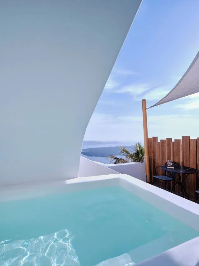 Aussenpool auf einer Terrasse mit Blick auf das Meer und ein Sonnensegel.