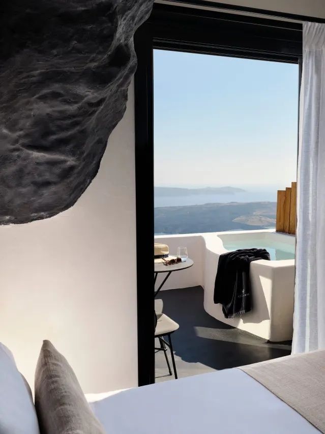 Blick durch eine Balkontür auf eine Terrasse mit Whirlpool und Meerblick.
