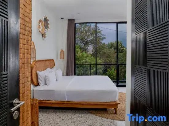 Hell eingerichtetes Schlafzimmer mit Doppelbett und großer Fensterfront zum Garten.