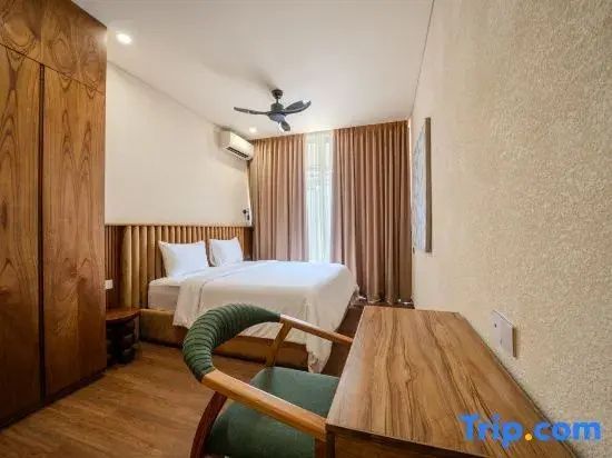 Schlafzimmer mit Doppelbett, Kopfteil aus Holzlamellen und einem Schreibtisch im Vordergrund.