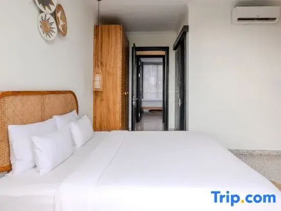Schlafzimmer mit weißem Doppelbett, Holzkleiderschrank und Blick in den angrenzenden Raum.