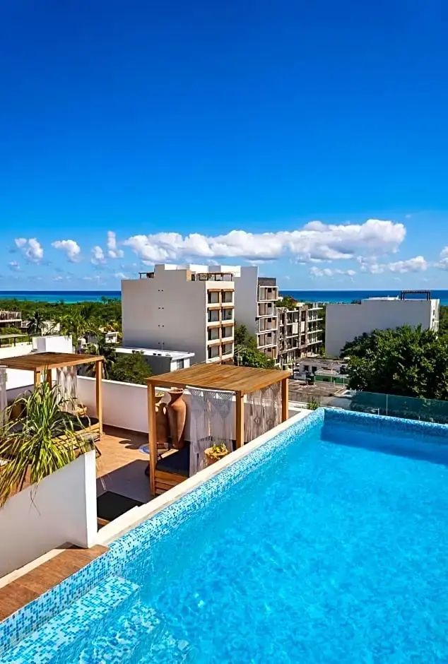 Pool auf der Dachterrasse mit Blick über weiße Gebäude bis zum blauen Meer.