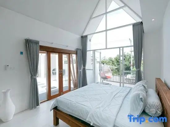 Helles Schlafzimmer mit Holzdoppelbett und hoher Fensterfront im Giebelstil.
