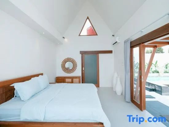 Helles Schlafzimmer mit hoher Decke, dreieckigem Fenster und Zugang nach draußen.