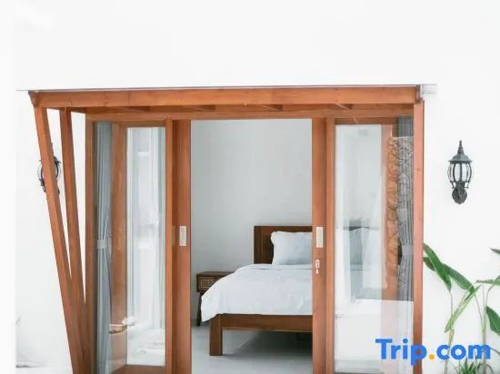 Blick durch Holzschiebetüren von außen auf ein Bett in einem hellen Schlafzimmer.