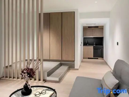 Raumteiler aus Holzlamellen neben einem Einbauschrank und einer Kitchenette im Zimmer.