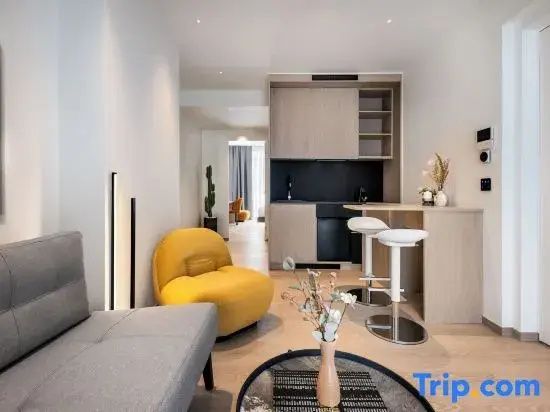 Wohnbereich mit gelbem Sessel, grauer Couch und einer kleinen Küchenzeile im Hintergrund.
