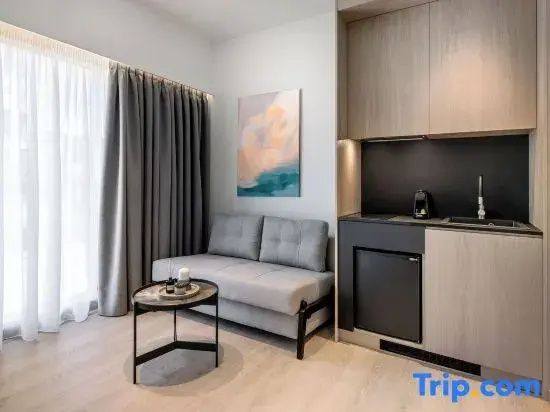 Modernes Zimmer mit grauer Schlafcouch, kleinem Beistelltisch und integrierter Küchenzeile.