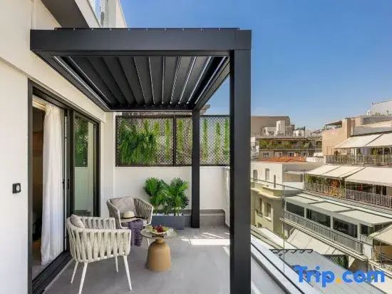 Überdachter Balkon mit zwei Sesseln und einem kleinen Tisch mit Blick auf die Stadt.