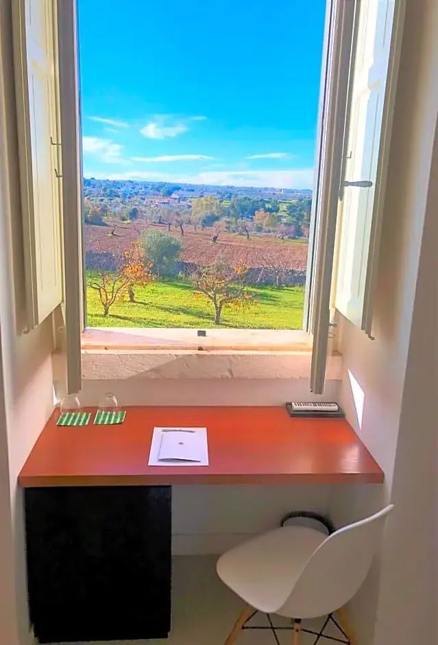 Blick durch ein geöffnetes Fenster auf eine grüne Landschaft mit Feldern.
