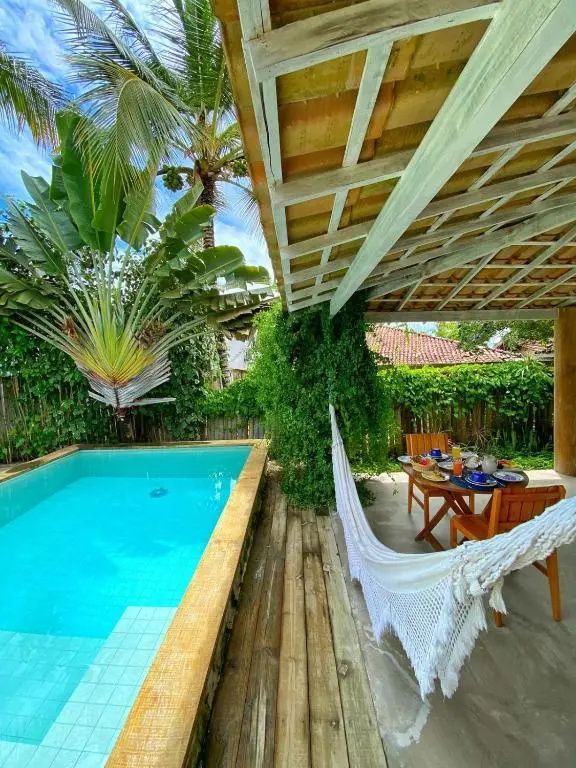 Überdachte Veranda mit Hängematte und Sitzgelegenheit neben einem Swimmingpool im Garten.