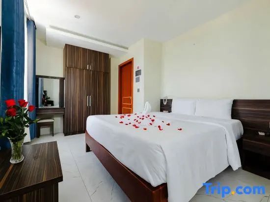 Helles Hotelzimmer mit großem Bett, Holzschrank, Schminktisch und Fliesenboden.