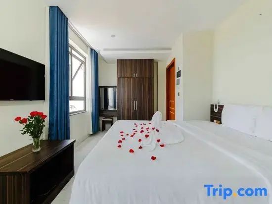 Hotelzimmer mit großem Doppelbett, roter Rosendekoration und dunklem Kleiderschrank.