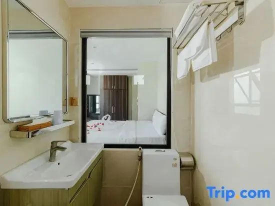 Badezimmer mit Waschtisch, Toilette und Glasfenster mit Blick ins Schlafzimmer.