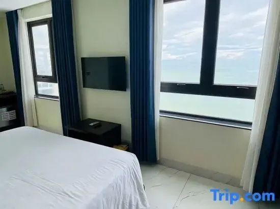 Helles Hotelzimmer mit Doppelbett, Flachbild TV und großem Fenster mit Blick auf das Meer.