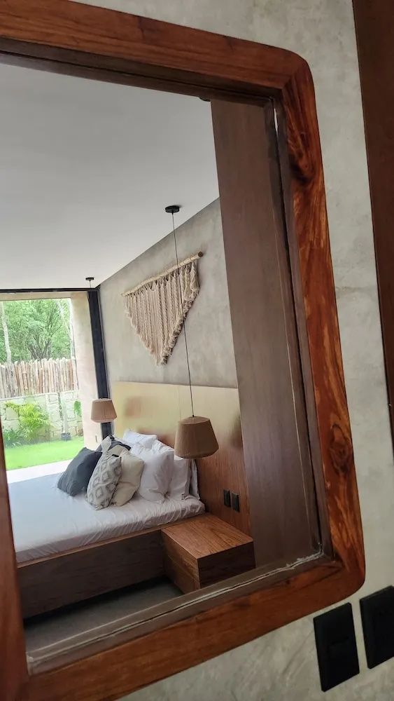 Schlafzimmer mit Doppelbett, Makramee Wanddekoration und Blick auf den grünen Garten.