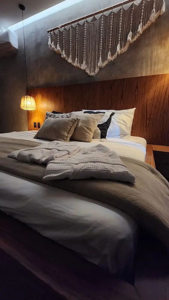 Doppelbett mit Holzkopfteil, bereitgelegten Bademänteln und warmer Beleuchtung.