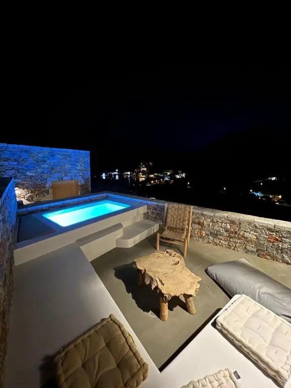 Blau beleuchteter Pool auf einer Terrasse bei Nacht mit Ausblick im Hintergrund.