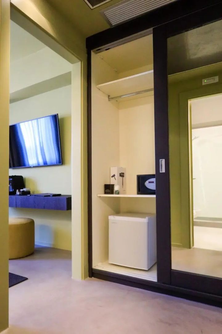 Garderobenschrank mit kleiner Minibar, Wertsachensafe und Blick in das Schlafzimmer.