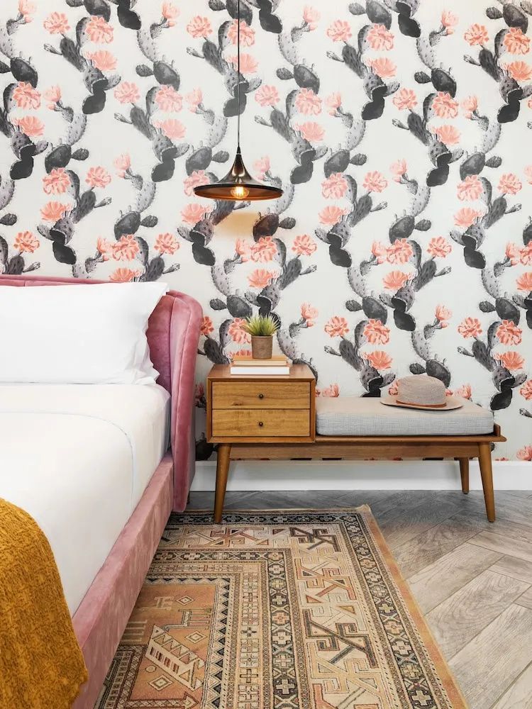 Doppelbett mit rosa Kopfteil neben Holznachttisch vor Wand mit Kaktusmuster